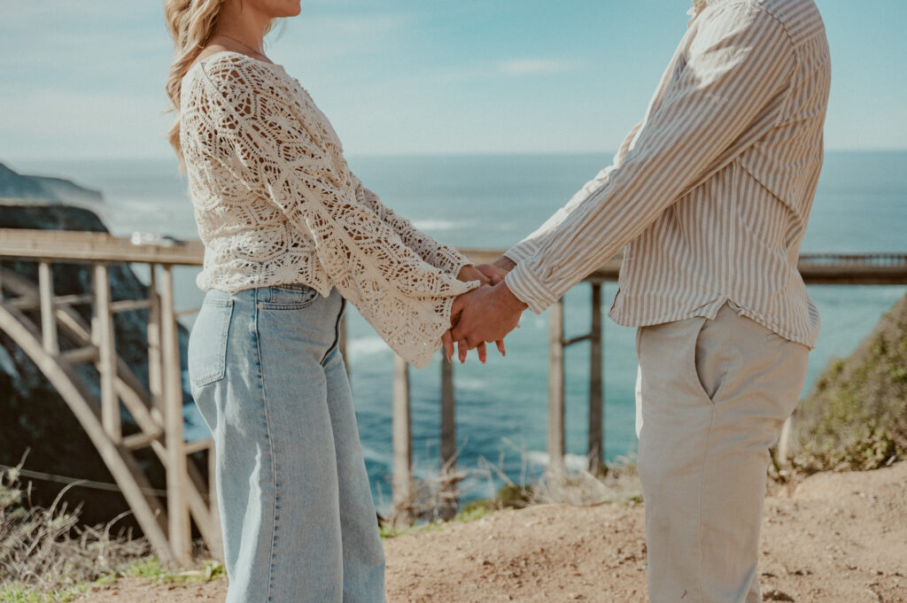 big sur engagement photos couples holding hands at bixby creek bridge in big sur, ca