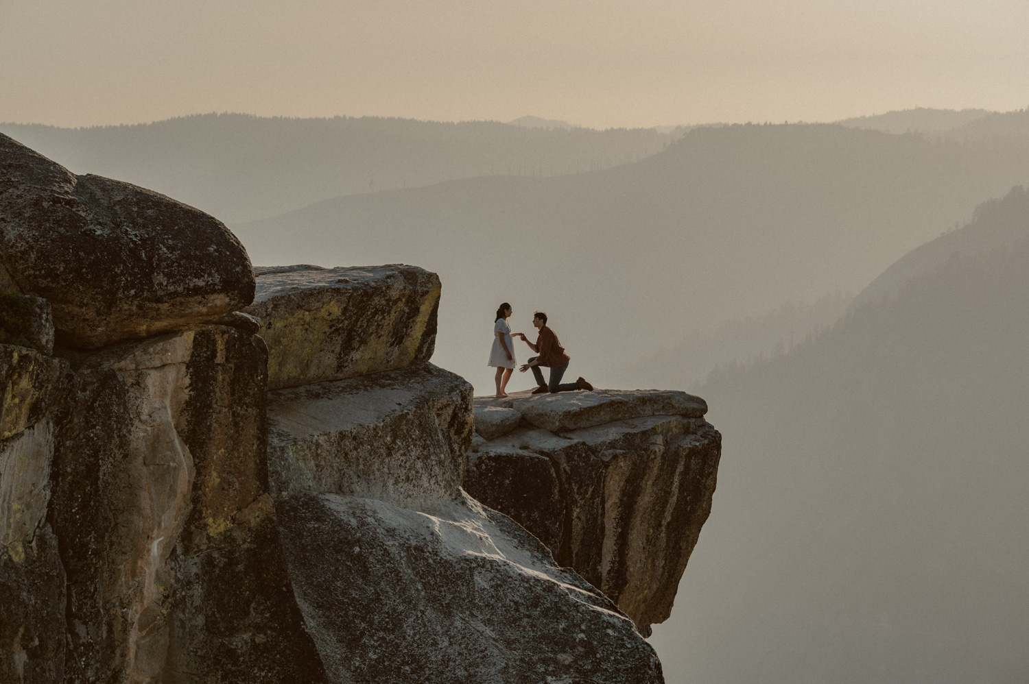 man gets down on one knee at taft point in yosemite